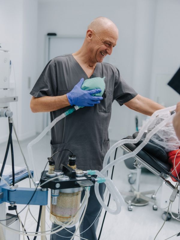 Anästhesist bedient Beatmungsbeutel und Narkosegerät, Vorbereitung auf Anästhesie im OP, moderne Anästhesiepraxis